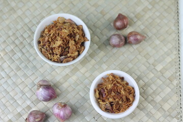 Bawang Merah Goreng or fried shallots, popular Indonesian food topping. Served on white ceramic bowl. Isolated background, copy space.
