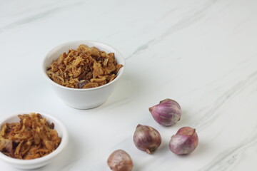 Bawang Merah Goreng or fried shallots, popular Indonesian food topping. Served on white ceramic bowl. Isolated background, copy space.