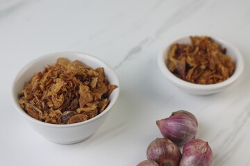 Bawang Merah Goreng or fried shallots, popular Indonesian food topping. Served on white ceramic bowl. Isolated background, copy space.