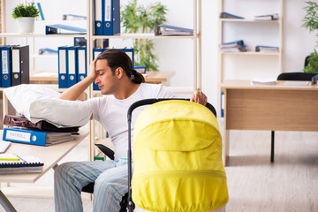 Young male employee looking after newborn at workplace