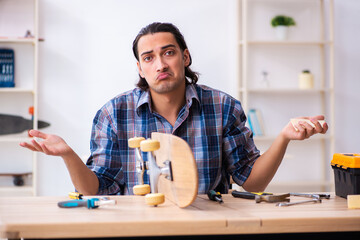 Young man repairing skateboard at workshop