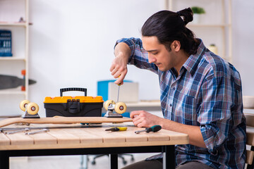 Young man repairing skateboard at workshop