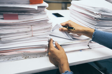 Business woman checking old document achieves on files of papers at busy work office.