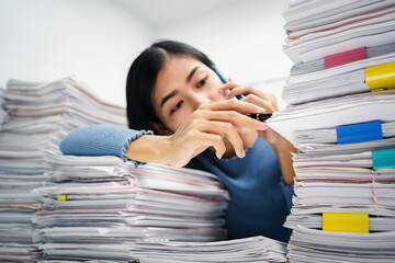Business wmployee woman working in stacks paper files for checking unfinished achieves busy at work.