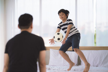 dad and son enjoy playing soccer football together in bedroom at home © Mongkolchon