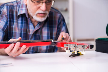 Senior male repairman repairing musical instruments at home