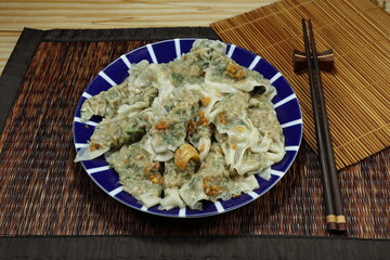 Pile of steamed Chinese wonton (dumplings) seasoning with garlic oil on the plate. Famous traditional appetizer menu in Asia restaurant. 