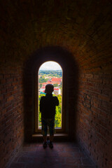 Boy looking at old stone window view on old town of Vilnius.