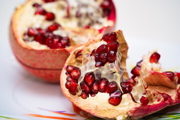Ripe peeled pomegranate on a plate. Healthy food rich in vitamins. Red juicy pomegranate close-up.
