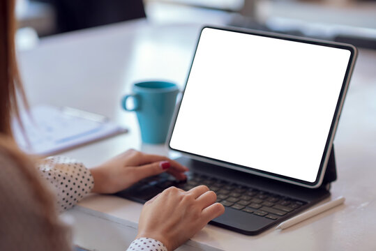 Close up. Woman hand typing on digital tablet keyboard with blank screen on desk at office.