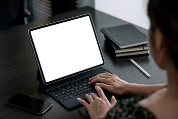 Close up. Woman hand typing on digital tablet keyboard with blank screen on desk at office.
