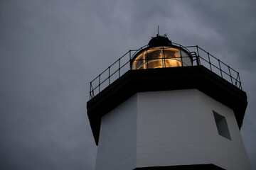 Lighthouse lighting up in the stormy night to lead the way for ships, ferries and fisherman.
