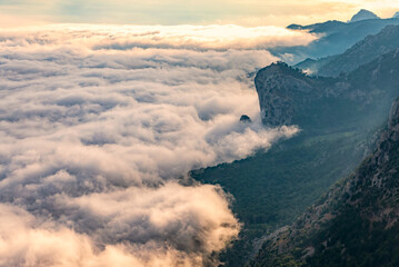 Majestic orange sunset over the rocky mountains and the valley in fog and clouds. Creamy fog covered the mountain valley in sunset light. Misty sunset over Crimea Mountains