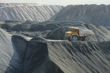 Mining dump truck in a stone quarry on the background of hills of crushed stone. © esalienko