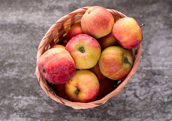 Fresh, ripe, delicious red apples in basket on gray background