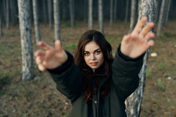 A woman in the forest in nature near the trees stretched her arms forward