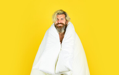 Positive morning. good morning routine. Caucasian bearded guy wrapped in white blanket. relax in a hotel room in blanket. bearded mature man lying at home. Carefree guy enjoying a new day