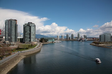 Obraz premium View of Vancouver False Creek waterfront skyline with snow mountain during springtime Seen from Cambie Bridge in the downtown of Vancouver, British Columbia, Canada.