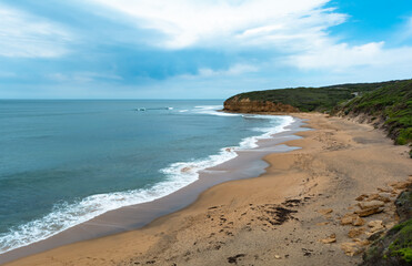 Panoramic view from hill Bells beach cliff with surfers in water cloudy sky iconic surfing spot Australia Victoria state Great ocean road