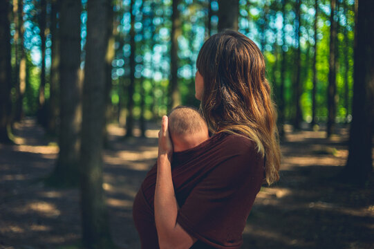 Mother with baby in sling standing in the forest