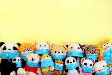 Many toys in protective face masks on yellow background, copy space. Coronavirus protection concept