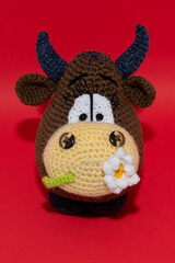 brown knitted handmade bull on the red background, symbol of 2021 year, bull