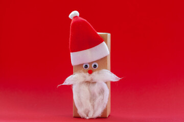 Creative christmas gift box in the form of Santa hat and beard on red background. Holiday greeting card