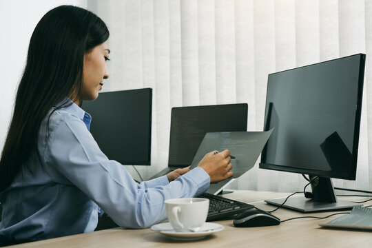 Asian woman software developers sitting in front of computers looking at computer codes on the screen.