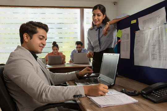 AN OFFICE EXECUTIVE WRITING DOWN INSTRUCTIONS GIVEN BY LEADER 	