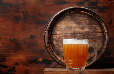 Mug of light lager beer and old wooden barrel