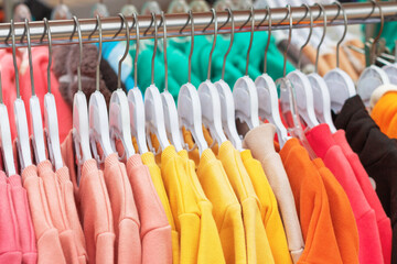 Bright children's clothes on hangers in a store close-up.