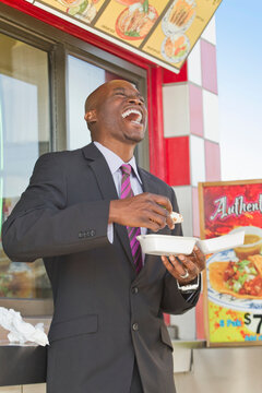 Laughing African American businessman eating lunch