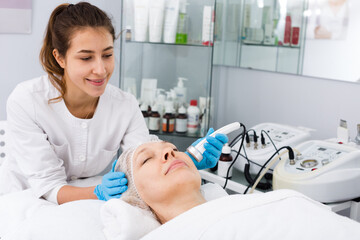 Obraz na płótnie Canvas Mature female client undergoing face beauty procedures in center