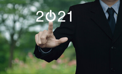 Businessman pressing 2021 start up business flat icon over blur flower and tree in park, Business happy new year 2021 cover concept