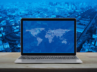 Global business words world map with modern laptop computer on wooden table over city tower, street, expressway and skyscraper, Global business online concept, Elements of this image furnished by NASA