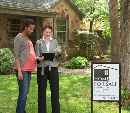 Pregnant woman and realtor looking at home for sale