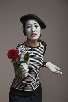 Woman in mime costume holding out rose