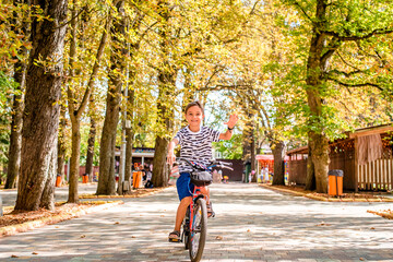 A happy boy rides his bike through a summer park. Joyful child cycling on vacation