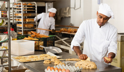Portrait of male baker working with dough and forming baguettes