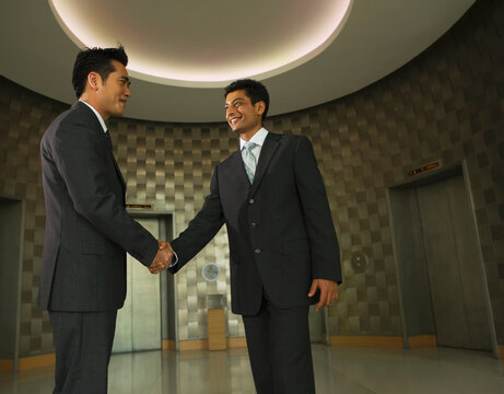 Businessmen shaking hands in office lobby