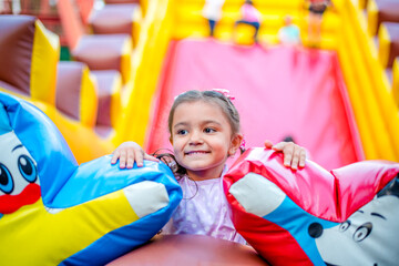 smiling little girl is playing in the park. She has fun on carousel 