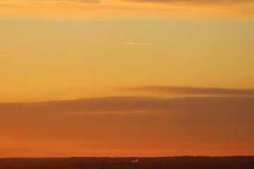 Sun below the horizon and clouds in the fiery dramatic orange sky at sunset or dawn backlit by the sun. Place for text and design