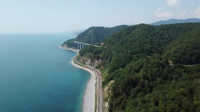Aerial view from drone of curve road with a car on the mountain with green forest in Russia