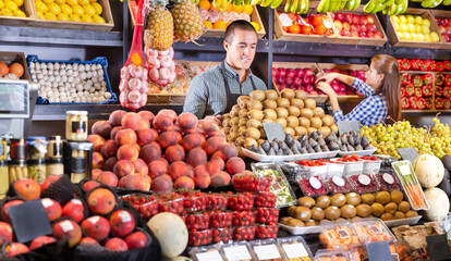 Obraz premium Portrait of male and female young shop assistants working responsibly in a fruit and vegetable shop