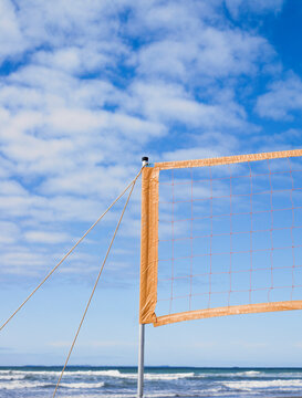 Beach volleyball net set up and waves and blue sky in background