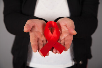 Woman's hands holding red AIDS awareness ribbon.