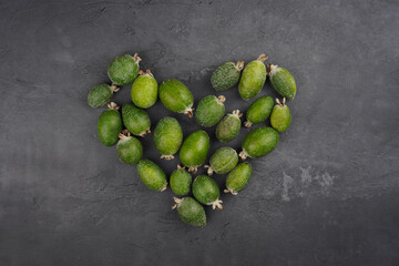 Feijoa heart shape on gray concrete background. Vitamin, immunity, recipe concept. Top view, copy space, flat lay