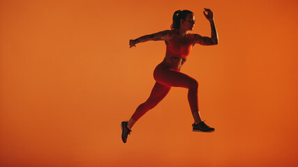 Fototapeta na wymiar Fit woman running on orange background