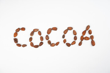 Word COCOA from beans on white background. Chocolate, dessert, recipe, menu concept. Top view, flat lay, copy space