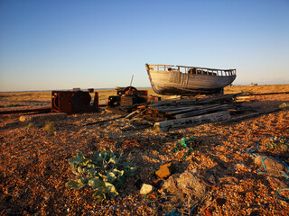 Fototapeta premium Abandoned fishing boat on Dungeness beach with discarded items scattered around - England.